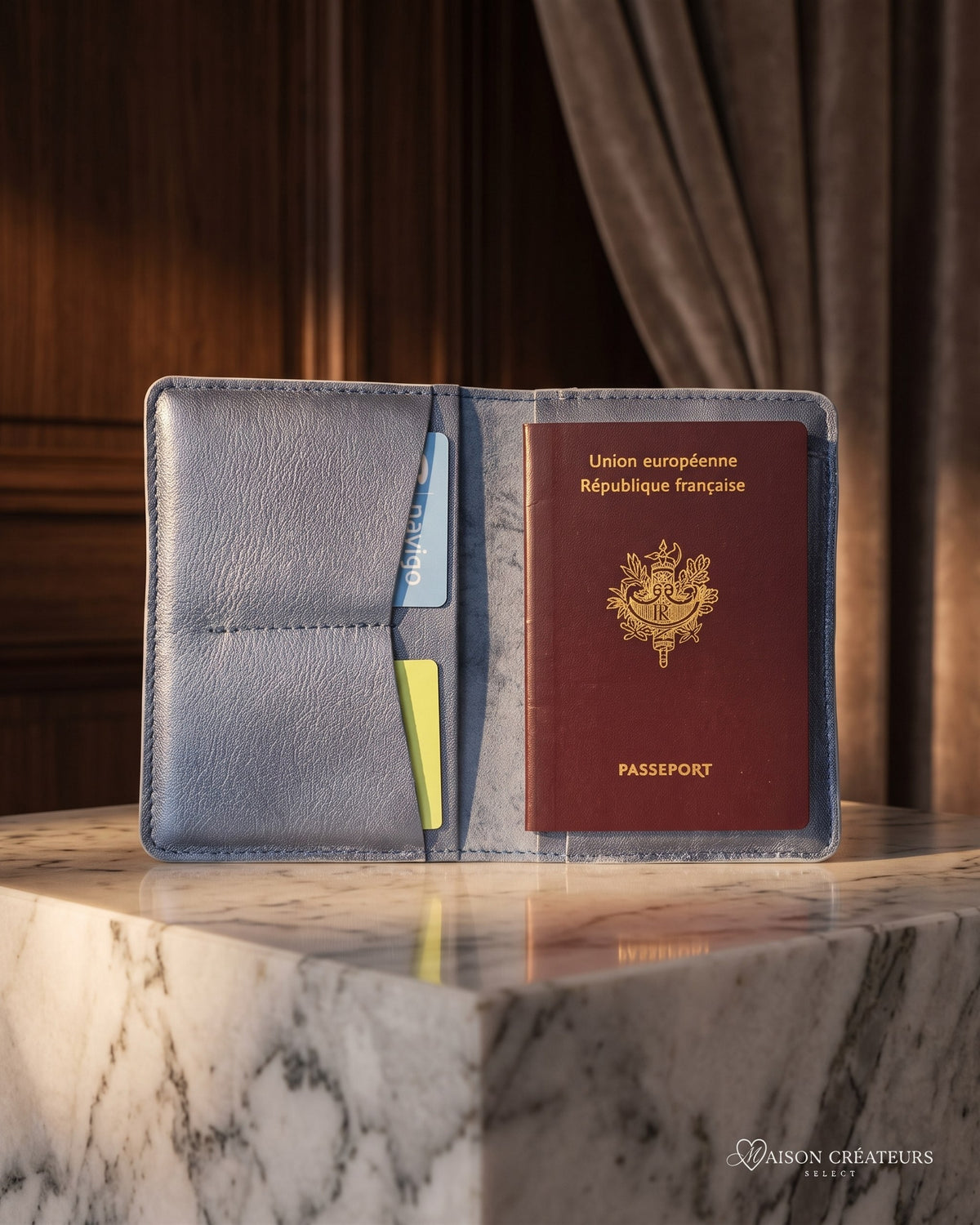 Le porte-passeport en cuir bleu marine posé sur un bloc de marbre blanc en boutique