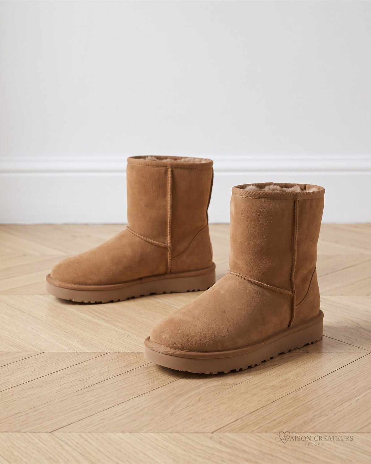 Bottes fourrées camel en suédine, posées sur un parquet en chevrons