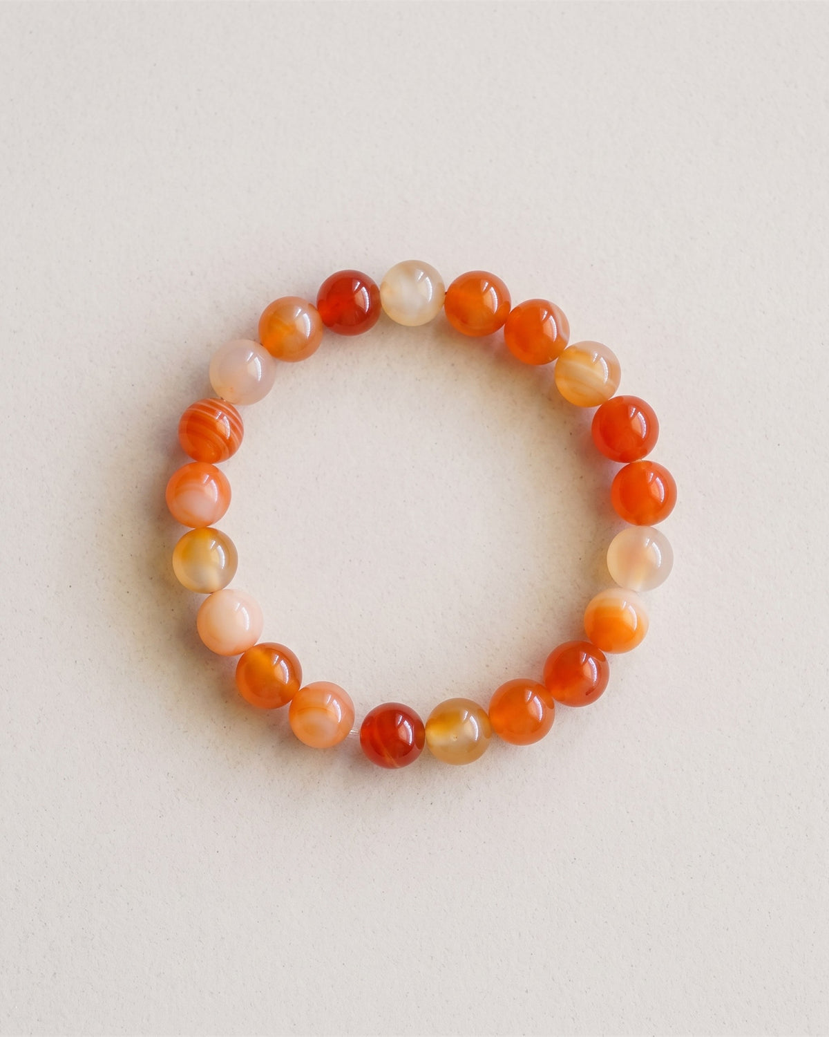 Bracelet en perles de cornaline orange, vue à plat sur fond pierre