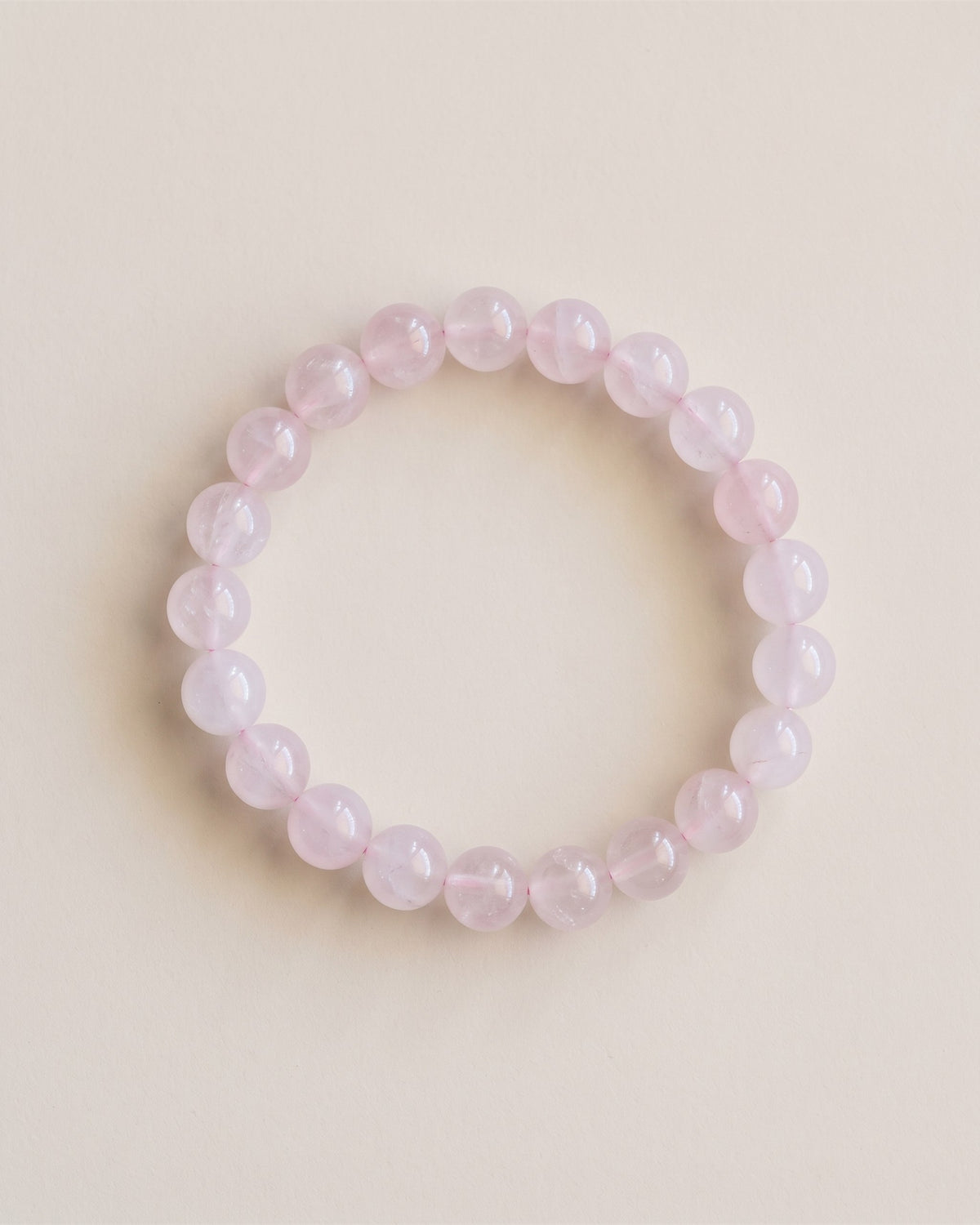 Bracelet en perles de quartz rose, vue à plat sur fond pierre