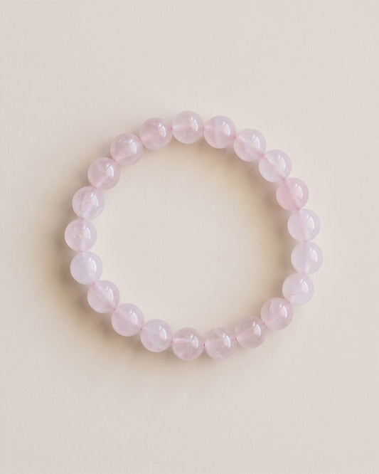 Bracelet en perles de quartz rose, vue à plat sur fond pierre