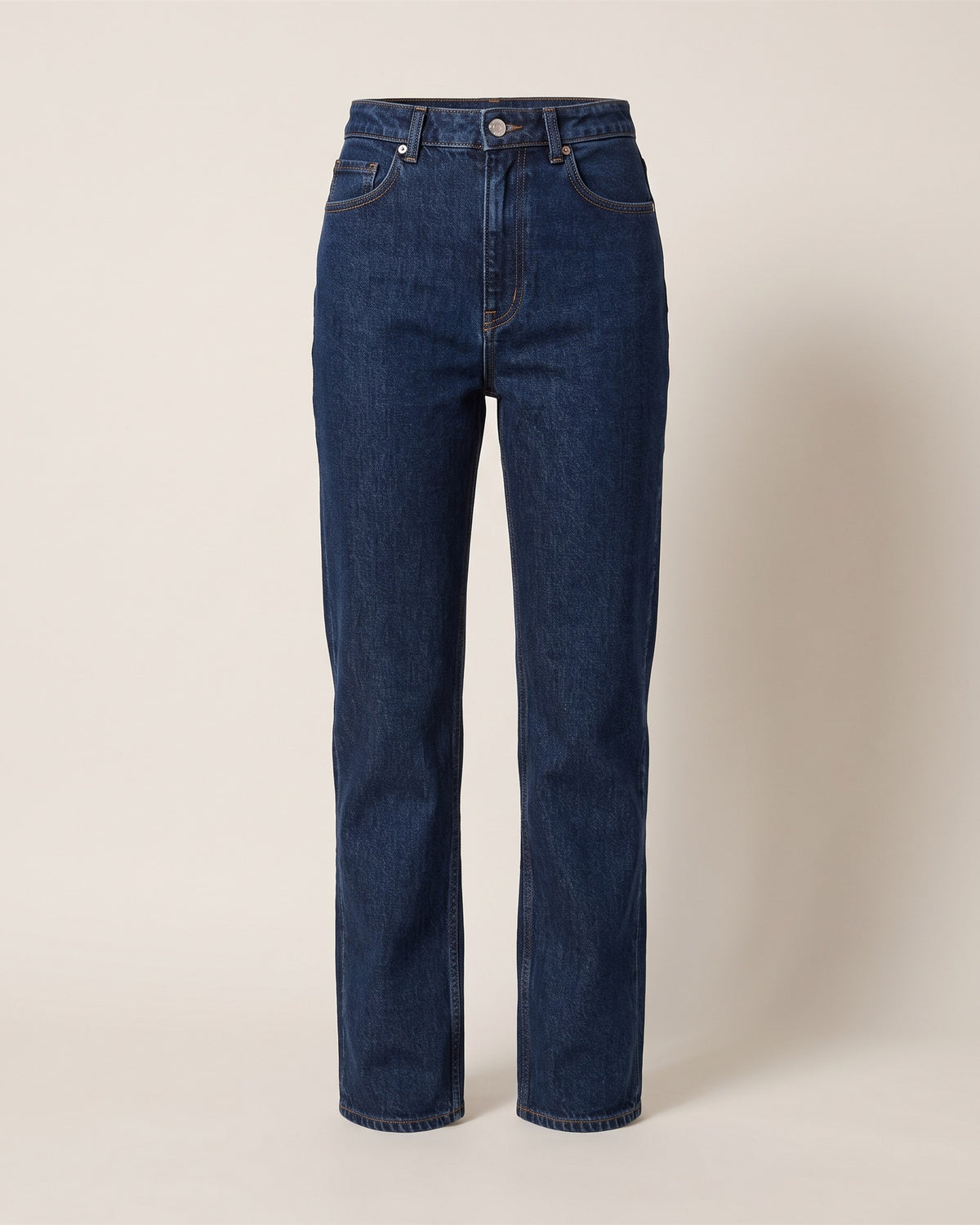 Jean droit taille haute en denim brut bleu foncé, vue de face sur fond pierre