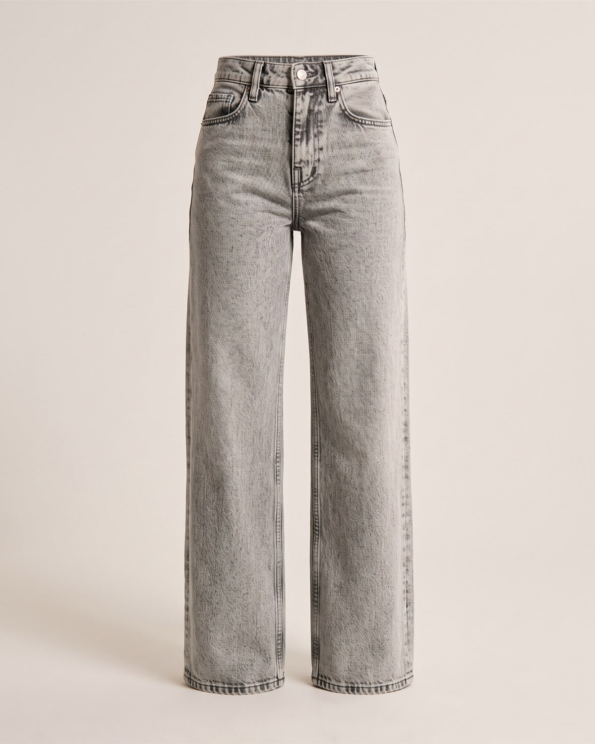 Jean large wide leg gris délavé taille haute, vue de face sur fond pierre