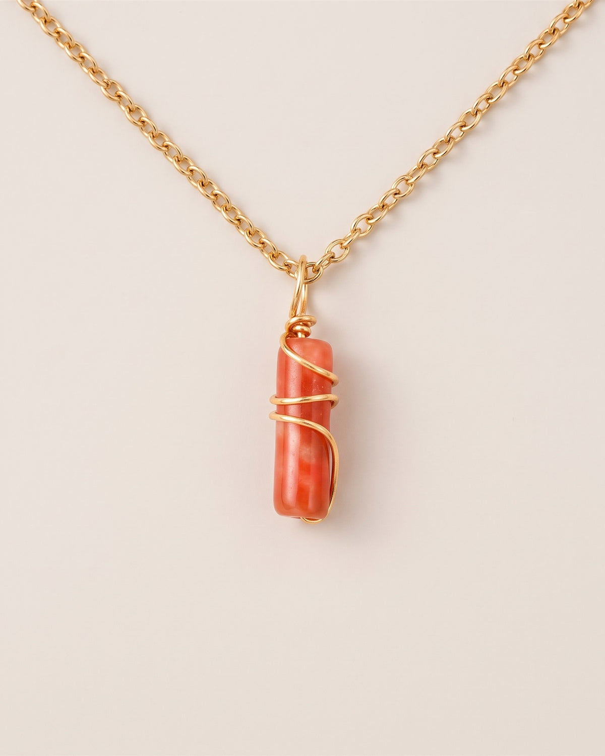 Pendentif mini pilier en jade Fleurs de prunier sur chaîne dorée, vue à plat sur fond pierre