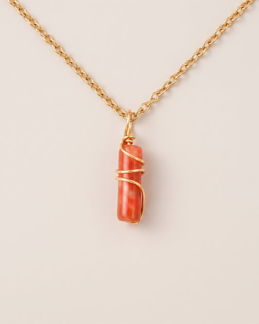 Pendentif mini pilier en jade Fleurs de prunier sur chaîne dorée, vue à plat sur fond pierre