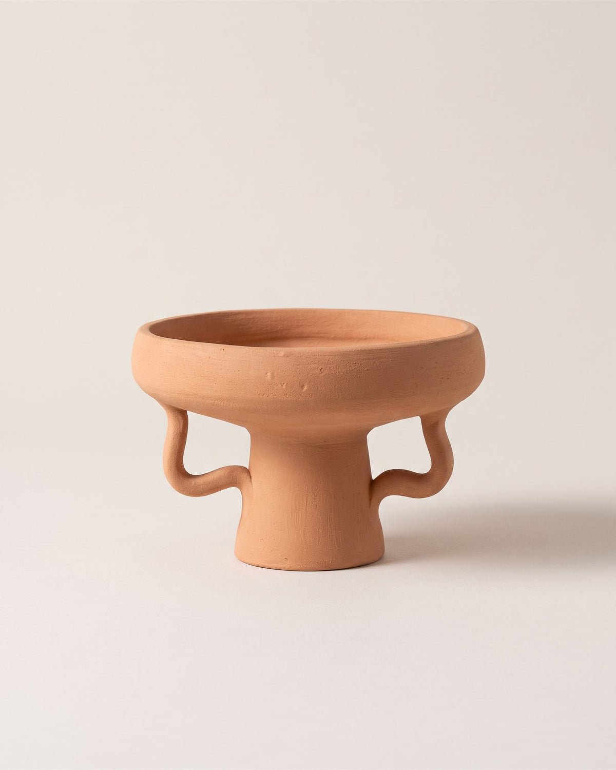 Coupe sur pied en céramique terracotta faite main, vue de face sur fond pierre
