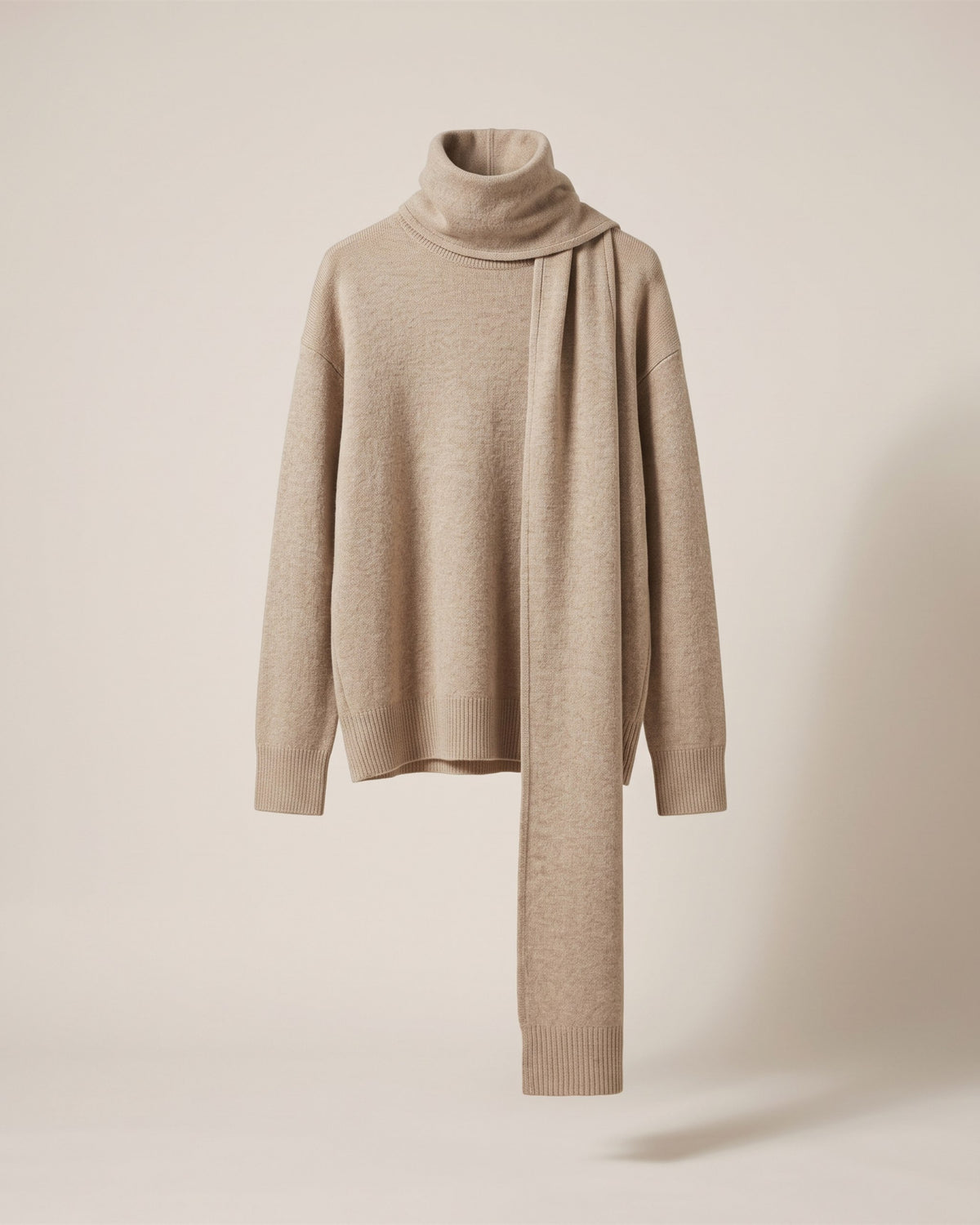 Pull écharpe beige en maille fine à écharpe intégrée, vue de face sur fond pierre