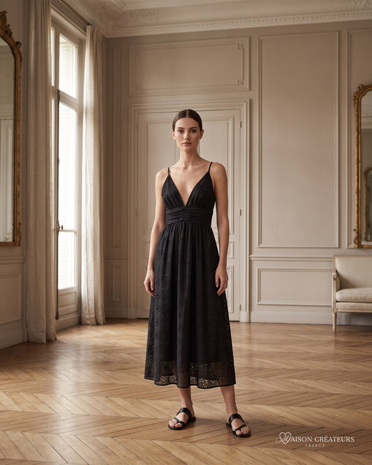 Robe Liora noire à fines bretelles et décolleté V, porté dans un salon haussmannien