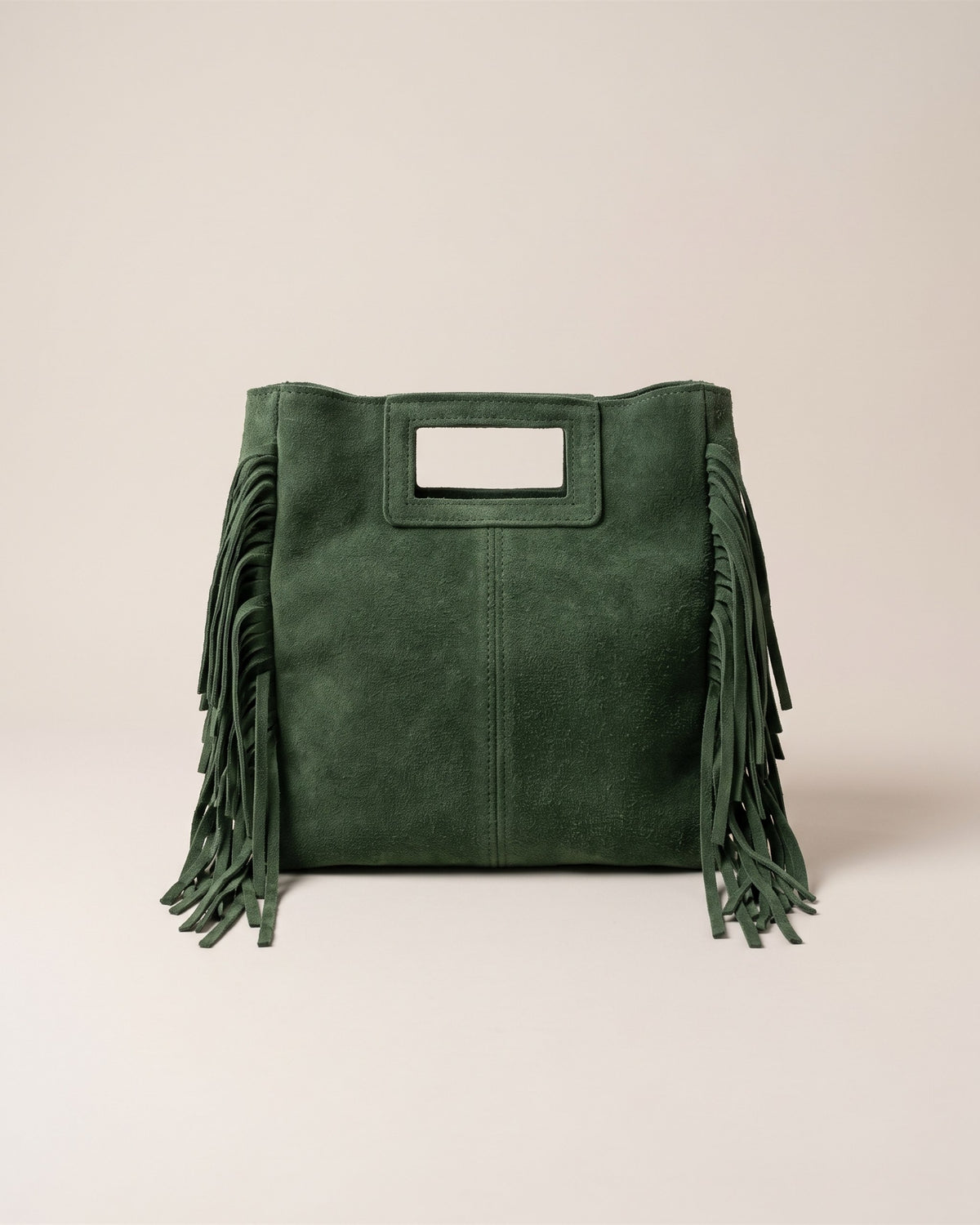 Le sac Marion en cuir daim vert, forme carrée à poignée découpée et franges sur les côtés, vue de face sur fond pierre