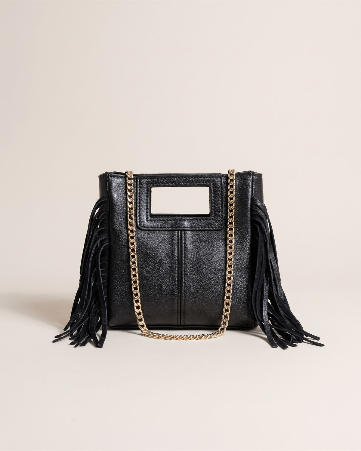 Le sac Marion Small en cuir irisé noir métallisé, forme carrée à poignée découpée, franges sur les côtés et chaîne dorée, vue de face sur fond pierre