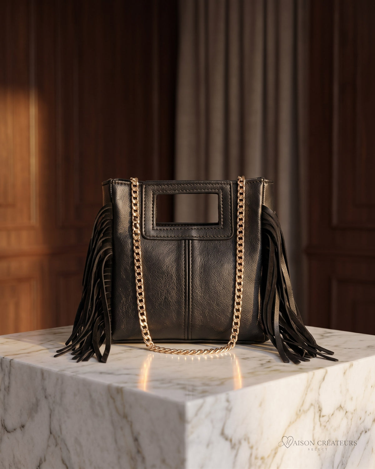 Le sac Marion Small en cuir irisé noir métallisé posé sur un bloc de marbre blanc en boutique