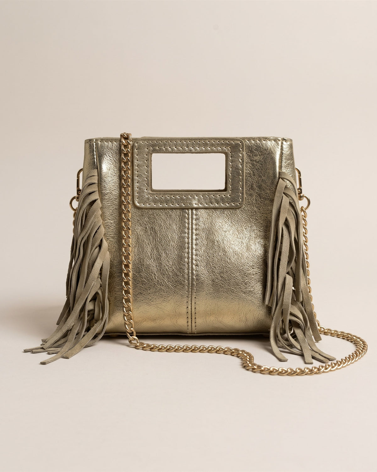 Le sac Marion Small en cuir irisé doré métallisé, forme carrée à poignée découpée, franges sur les côtés et chaîne dorée, vue de face sur fond pierre