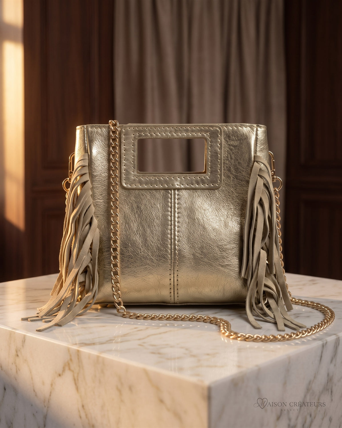 Le sac Marion Small en cuir irisé doré métallisé posé sur un bloc de marbre blanc en boutique