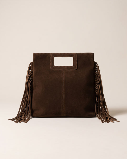 Le sac Solène en cuir suède italien chocolat, forme rectangulaire haute à poignée découpée et franges sur les côtés, vue de face sur fond pierre