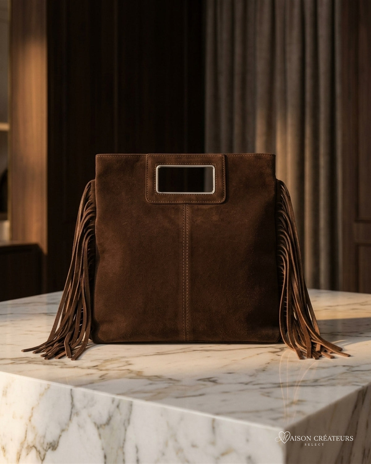 Le sac Solène en cuir suède italien chocolat posé sur un bloc de marbre blanc en boutique