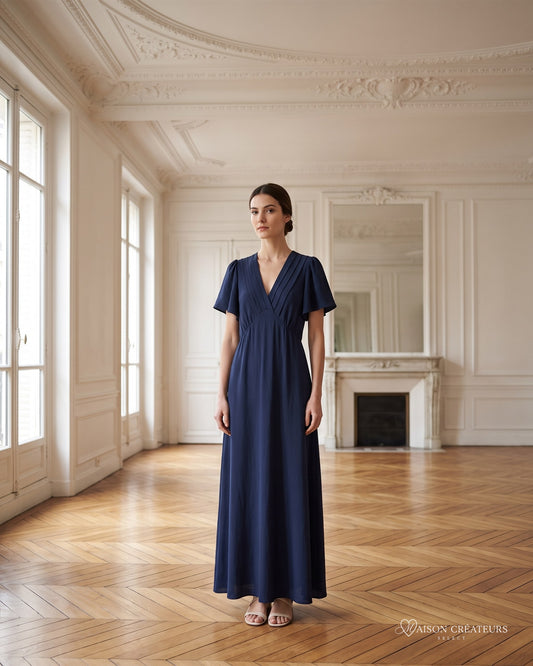 Robe longue Céleste bleu marine à col V et manches tulipe, porté dans un salon haussmannien
