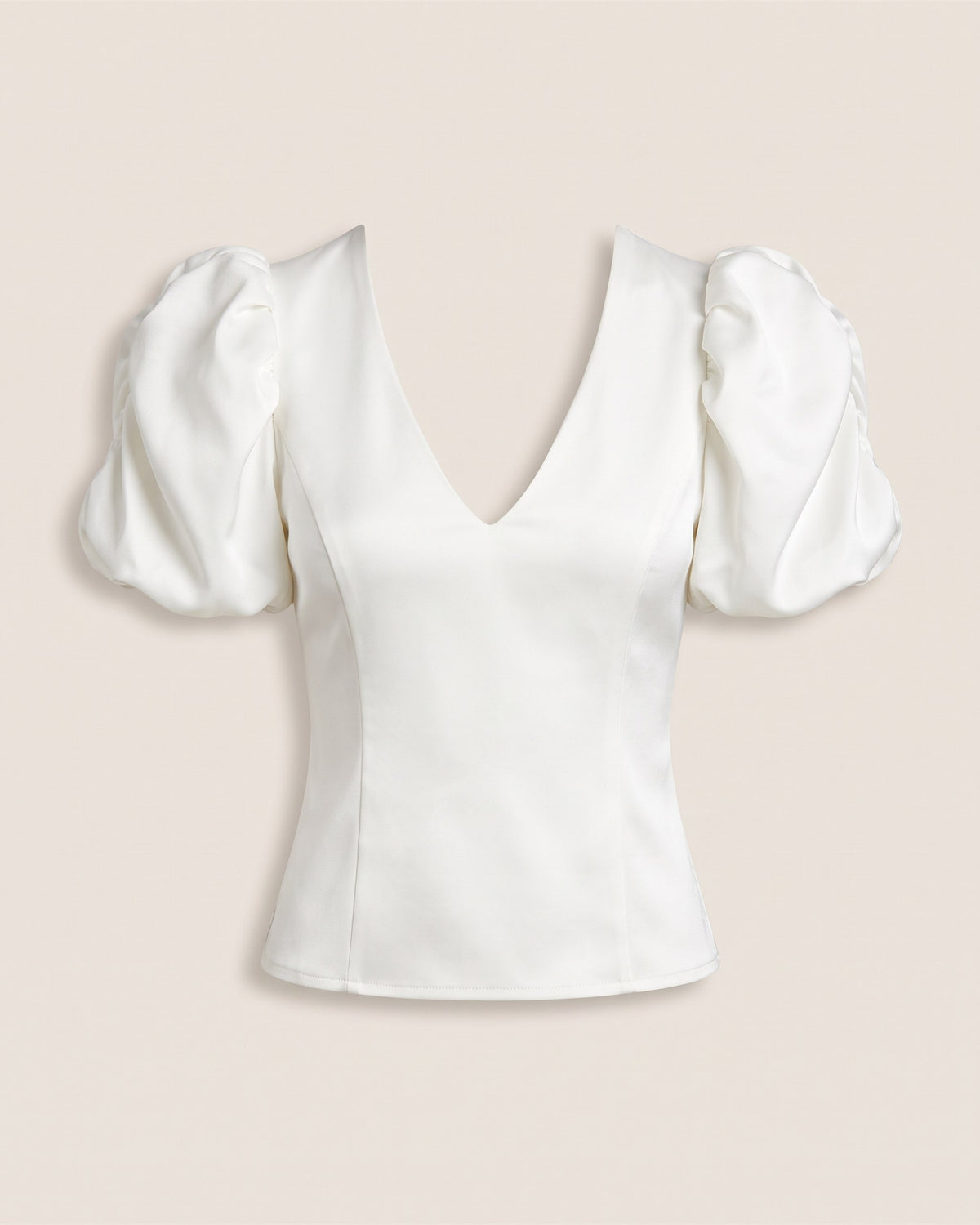 Top blanc à manches bouffantes et décolleté V, vue de face sur fond pierre