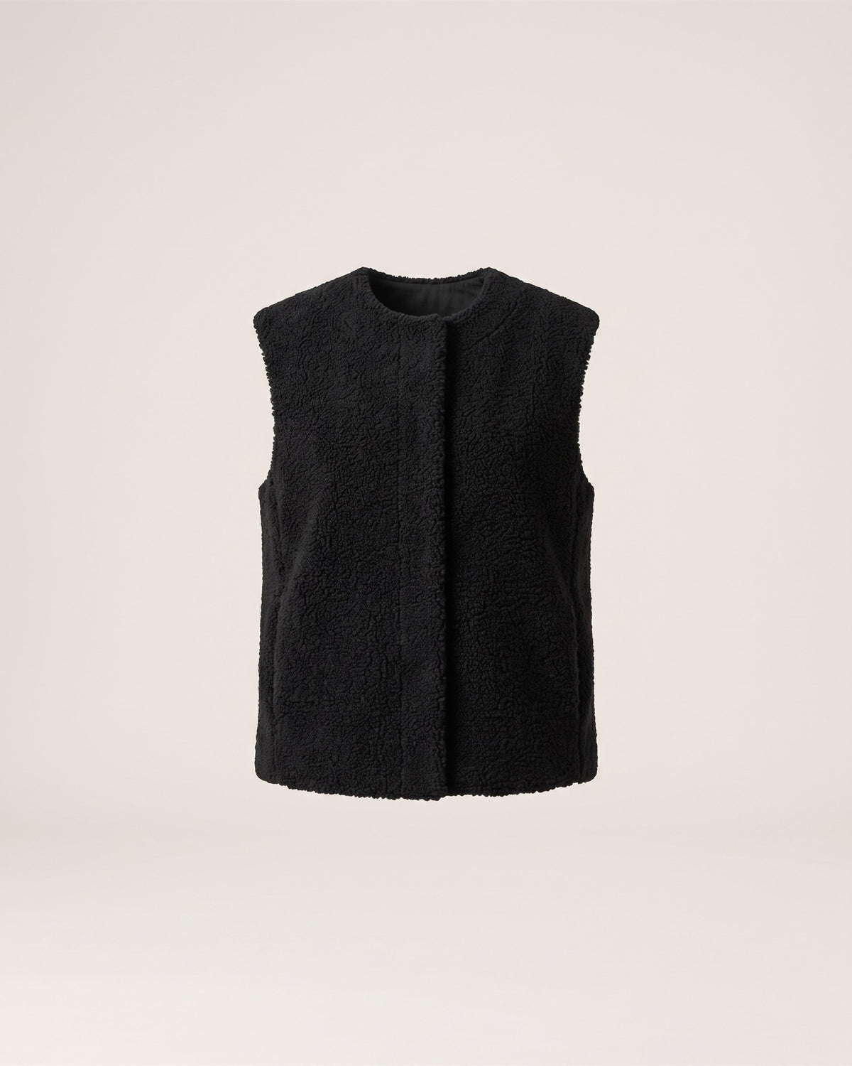 Veste sans manches noire en moumoute, vue de face sur fond pierre